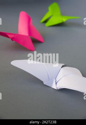 Grünes, rosafarbenes und weißes Papier mit Schmetterling Origami isoliert auf grauem Hintergrund Stockfoto