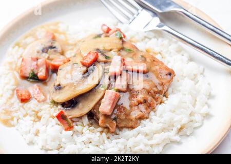 Schweinefilet mit Pilzsauce und Schinken mit weißem Reis serviert Stockfoto