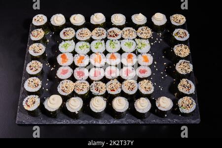 Japanisches Sushi-Set. Verschiedene Arten von Maki Rollen auf einem Teller auf einem Steingrund. Stockfoto