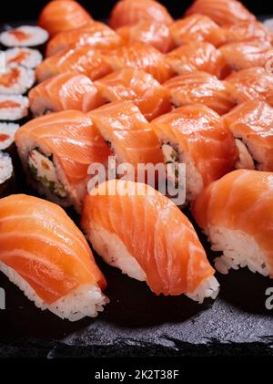 Philadelphia Sushi mit Avocado, Frischkäse, Lachs und Masago-Kaviar auf schwarzem Schiefer. Stockfoto