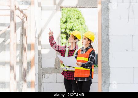 Architekt und Bauherr besprechen den Plan mit dem Bauplan des Gebäudes auf der Baustelle Stockfoto