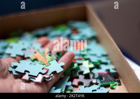 Die Hände bauen das Puzzle zusammen, und die Teile werden zusammengesetzt Stockfoto