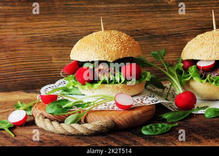 Hausgemachte Burger mit Rindfleisch, Radieschen, Salat, auf hölzernen Hintergrund serviert. Stockfoto