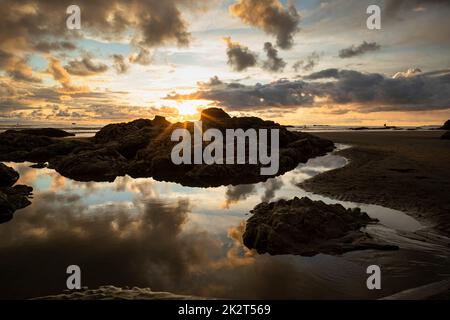 WA22048-00...WASHINGTON - Sonnenstrahlen von der untergehenden Sonne und Wolken, die sich in einem Tidepool am Ruby Beach im Olympic National Park spiegeln. Stockfoto