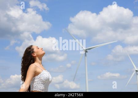 Eine Frau, die frische Luft in einem Windpark atmet Stockfoto