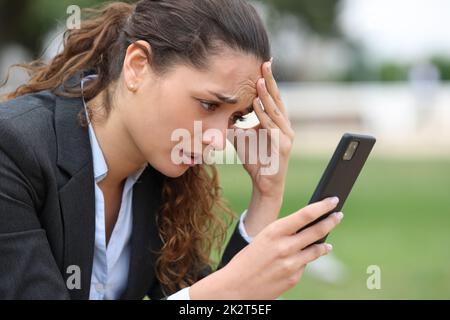 Besorgte Führungskraft überprüft schlechte Nachrichten auf dem Handy Stockfoto