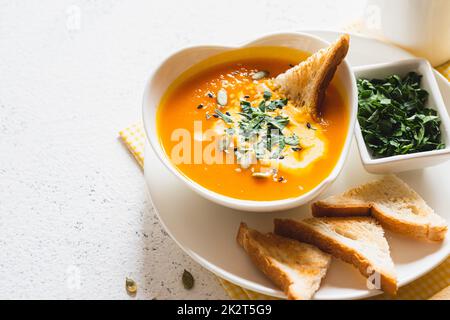 Vegetarische Herbstsuppe mit Kürbis und Karotten mit Sahne und Samen. Comfort Food, Herbst und Winter gesundes Slow Food Konzept Stockfoto