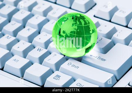 Grüne Kristallkugel der Erde auf einer Computertastatur Stockfoto