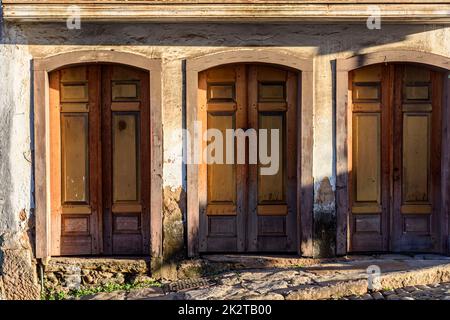 Alte Holztüren, die durch die Zeit an der Fassade eines Hauses im Kolonialstil verdorben wurden Stockfoto