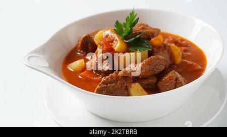 Rindergulasch, Suppe und ein Eintopf, bestehend aus Rindersteak, Kartoffeln und viel Paprika. Traditionelles ungarisches Essen. Stockfoto