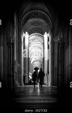 Die Leute, die den Korridor im Café Marly im Louvre-Museum entlang laufen, vertikal, Graustufen Stockfoto