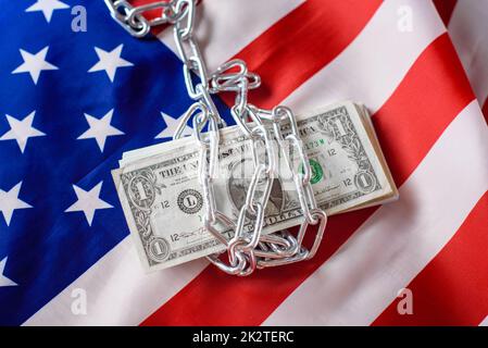 Verkettete US-Dollar-Scheine, die den Steuerzahlern wegen Inflation vorenthalten wurden, auf US-Flagge Hintergrund. Stockfoto