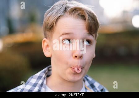 Der freche Teenager macht Gesichter an der Kamera, zeigt seine Zunge und schwelgt Stockfoto