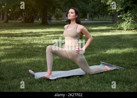 Eine schöne junge Frau, die im Park Yoga oder Outdoor-Sport macht. Stockfoto