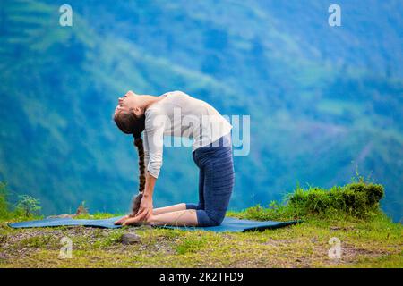 Frau tut Yoga Asana Ustrasana Kamel-Pose im freien Stockfoto