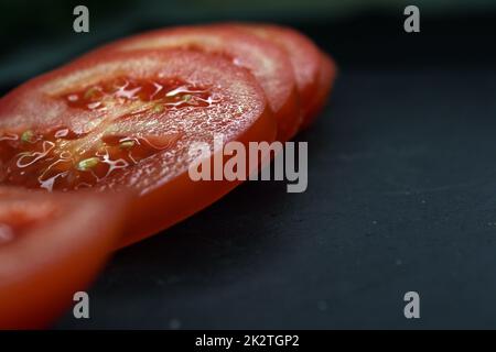 Nahaufnahme von Tomatenscheiben auf schwarzem Hintergrund Stockfoto