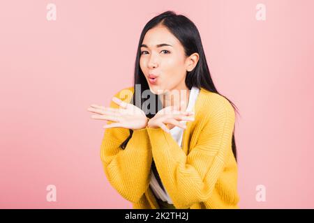 Junge Frau, die steht und Luft küsst, irgendwas auf der Handfläche Stockfoto