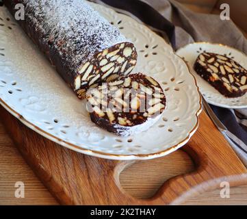 Fauler Kuchen oder Mosaikkuchen . Hausgemachter, nicht gebackener Schokoladenkuchen auf einem Holztisch Stockfoto