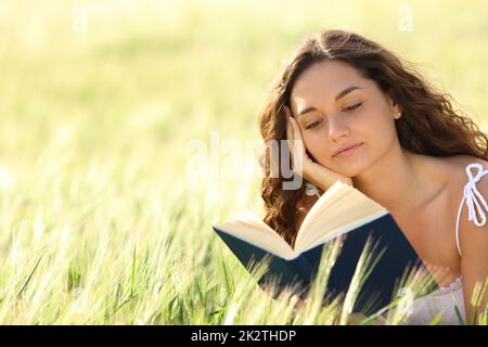 Eine Frau, die in einem Weizenfeld ein Buch liest Stockfoto