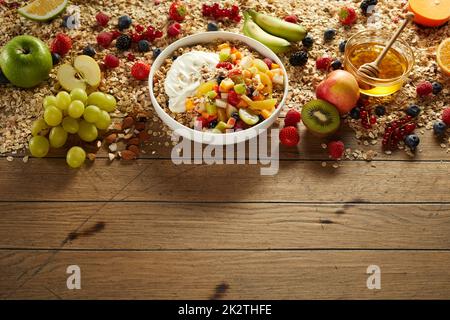 Köstliche Frühstückschüssel mit Obst und Beeren auf einem Holztisch Stockfoto