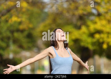 Aufgeregter Teenager, der in einem Park die Arme ausstreckt Stockfoto