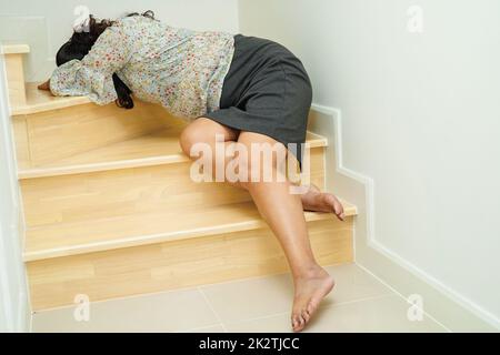 Asiatische Dame Frau Verletzungen durch Herunterfallen auf rutschigen Oberflächen Treppen zu Hause. Stockfoto