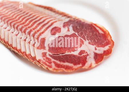 Italienischer, getrockneter coppa mit Gewürzen. Roher Schinken. Crudo oder Jamon auf einem weißen Teller. Platz für eine Inschrift. Stockfoto