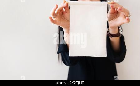 Junge Geschäftsfrau in einem schwarzen Anzug zeigt eine weiße Plakatwand auf einem weißen, isolierten Hintergrund. Für die Beschriftung auf dem Poster platzieren. Stockfoto