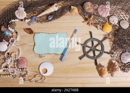 Leeres Papier mit verbrannten Kanten auf Holzhintergrund mit Meeresmuscheln und Fischernetz. Nautisches und Küstenthema Stockfoto