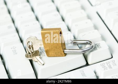 Ein entriegeltes Vorhängeschloss auf einer Computertastatur Stockfoto