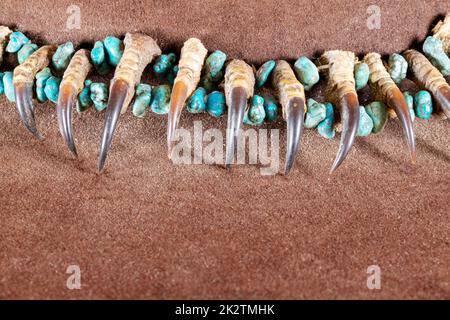Old Native American Lakota Halskette aus Raptor-Krallen und türkisfarbenen Steinen auf braunem Filz Stockfoto