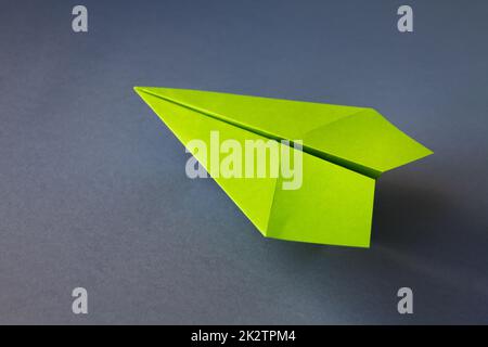 Grünpapierflugzeug Origami isoliert auf grauem Hintergrund Stockfoto