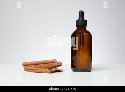 Braune Glasflasche mit Pipette auf blauem Hintergrund. Behälter für Kosmetika Stockfoto