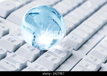 Crystal Earth Globus auf Computertastatur Stockfoto
