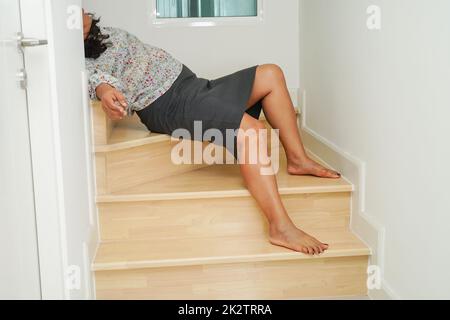 Asiatische Dame Frau Verletzungen durch Herunterfallen auf rutschigen Oberflächen Treppen zu Hause. Stockfoto