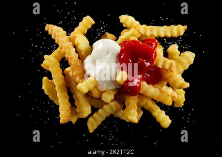 Leckeres Crinkle, gebraten mit Ketchup und Mayonnaise auf einem schwarzen Tisch Stockfoto