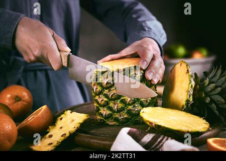 Eine anonyme Frau, die frische Ananas schält Stockfoto