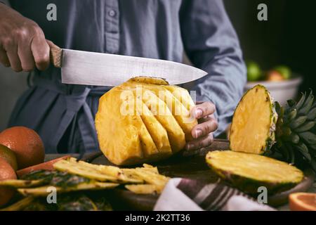 Erntegutfrau schneidet geschälte Ananas Stockfoto