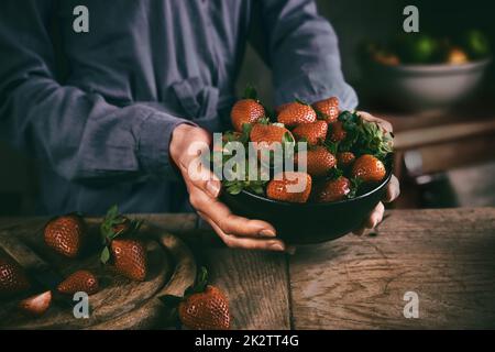 Die Hausfrau stellt eine Schüssel Erdbeeren auf den Tisch Stockfoto