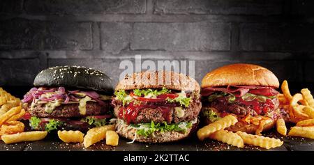 Leckere Hamburger und Pommes Frites im dunklen Studio Stockfoto