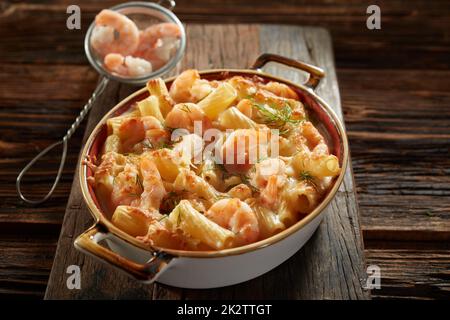 Schmackhafte cremige Pasta mit Meeresfrüchten in Kochtopf, serviert auf Holzfläche Stockfoto