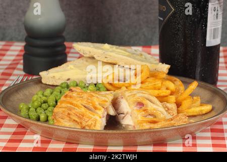 golden Baked Chicken und Speck Gitterkuchen mit Chips und Erbsen Stockfoto