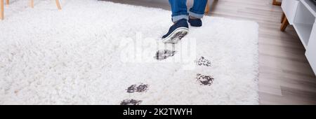 Person, Die Mit Schlammigen Fußabdrücken Auf Dem Teppich Läuft Stockfoto