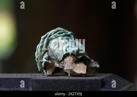 Gebrochener Kopf eines Kruzifixes auf einem Grabstein Stockfoto