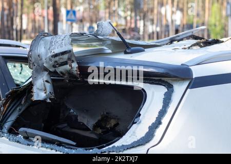 Hat während des Krieges in der Ukraine ein Auto erschossen. Ein Auto voller Zivilisten mit Splitterlöchern von Explosionen. Autounfall. Autofriedhof. Spuren von Schüssen am Körper. Das Fahrzeug wurde nach dem Beschuss beschädigt. Stockfoto