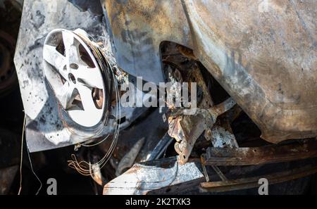 Kaputte und verbrannte Autos auf dem Parkplatz, Unfall oder vorsätzlicher Vandalismus. Verbranntes Auto. Folgen eines Autounfalls. Durch Brandstiftung beschädigt. Mülldeponie ziviler Fahrzeuge, die von russischen Truppen in der Ukraine erschossen wurden. Stockfoto