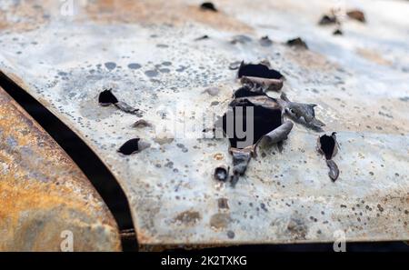 Verbrannte Autokarosserie voller Kugeln. Russlands Krieg gegen die Ukraine. Erschossen vom russischen Militärauto von Zivilisten während der Evakuierung. Spuren von Kugeln und Muschelfragmenten. Stockfoto