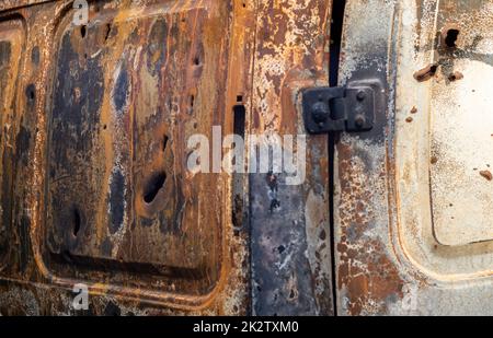 Verbrannte Autokarosserie voller Kugeln. Russlands Krieg gegen die Ukraine. Erschossen vom russischen Militärauto von Zivilisten während der Evakuierung. Spuren von Kugeln und Muschelfragmenten. Stockfoto