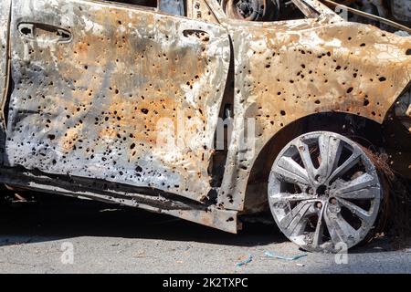 Verbrannte Autokarosserie voller Kugeln. Russlands Krieg gegen die Ukraine. Erschossen vom russischen Militärauto von Zivilisten während der Evakuierung. Spuren von Kugeln und Muschelfragmenten. Stockfoto