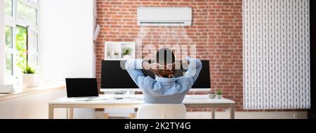Geschäftsmann, Der Sich Im Büro Mit Klimaanlage Entspannen Kann Stockfoto